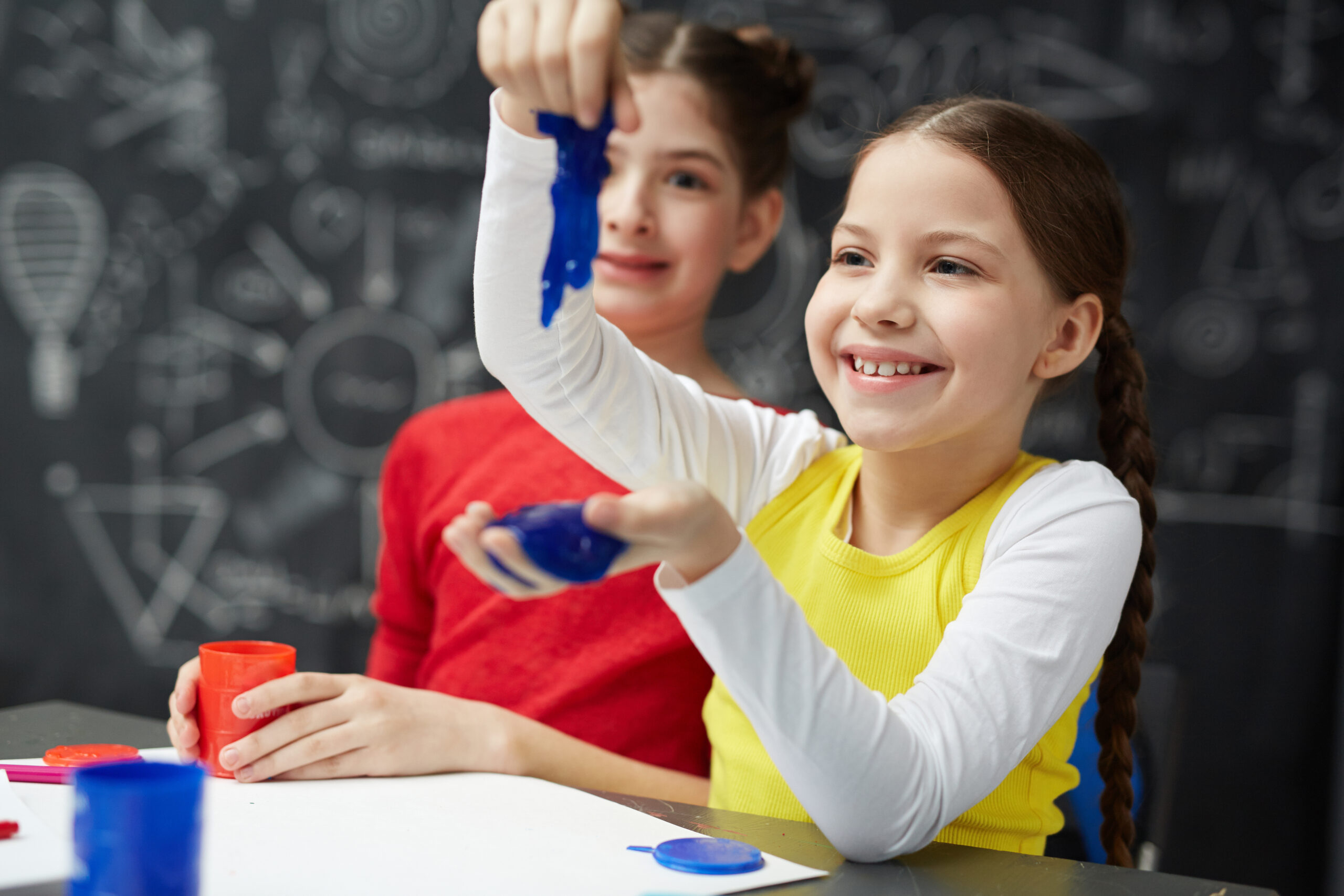 Smiling girl playing with blue slime in school